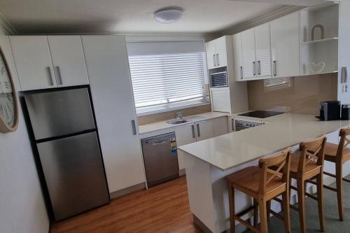 a kitchen with white cabinets and a black refrigerator at Spectacular Waterfront Views Discover the Hidden Gem of Cronulla with our Rare 3 Bedroom Apartment with Free Parking in Cronulla