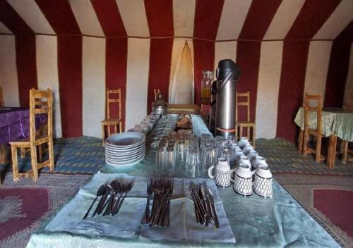 a table in a tent with plates and utensils at Sultan Luxury Camp in Merzouga