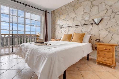 1 dormitorio con 1 cama grande y pared de piedra en Villa Christisay en Salobre