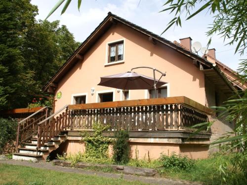a house with a balcony with an umbrella at Forest Retreat in Vosges in Hanviller