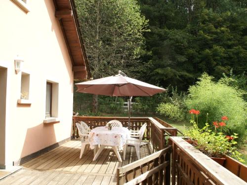 a wooden deck with an umbrella and a table and chairs at Forest Retreat in Vosges in Hanviller