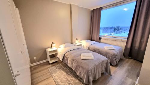 two beds in a room with a large window at Kotka Orange Apartments Tapuli in Kotka