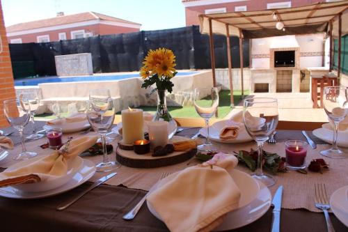 La Casa de Taramona في Barcience: طاولة مع صحون و كاسات و مزهرية مع عباد الشمس