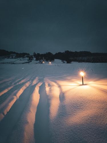 a snow covered field with a light on top of it at Jurty z widokiem, prywatna balia- DZIKOLAS GLAMPING in Krasnobród