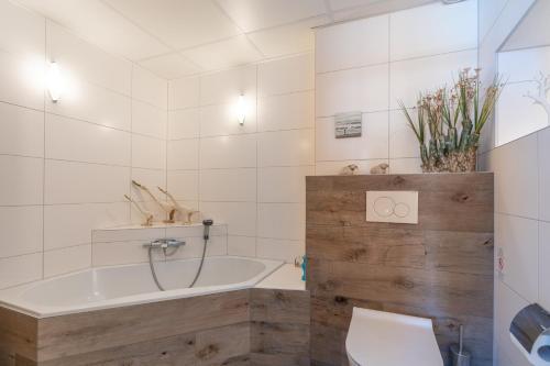 a bathroom with a tub and a toilet and a sink at Appartementencomplex Juliana 114 in De Koog