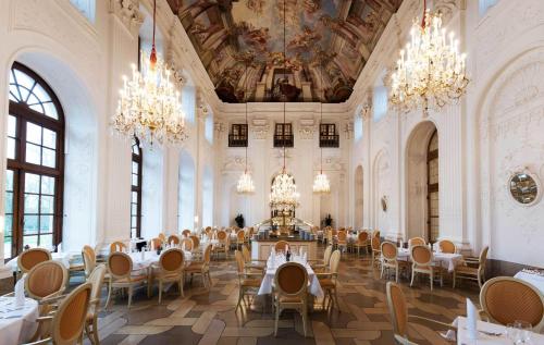 a dining room with tables and chairs and chandeliers at Maritim Hotel Am Schlossgarten in Fulda