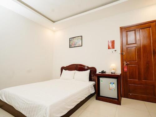 a bedroom with a white bed and a wooden door at NAM CẦN THƠ HOTEL in Ấp Phú Thạnh (4)