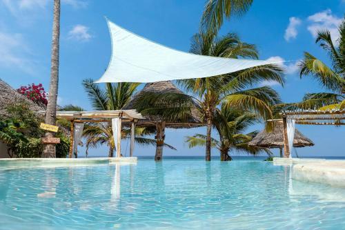 - une piscine dans un complexe avec des palmiers dans l'établissement Aya Beach Resort, à Kizimkazi