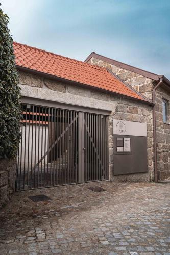 a stone building with a gate and a door at Villã - Casas de Campo in Paredes