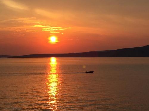 a boat on the water at sunset at Apartments Miki in Donja Klada