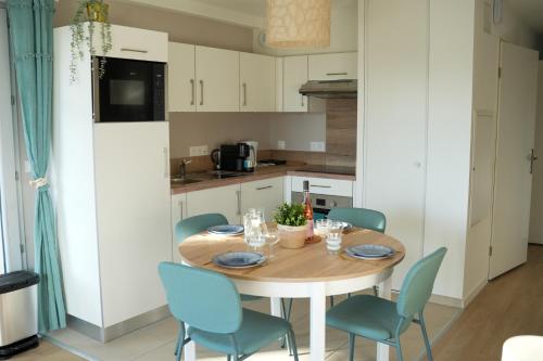 une cuisine avec une table en bois et des chaises bleues dans l'établissement Appartement neuf, avec terrasse, parking et ascenseur, à Saint-Valery-sur-Somme