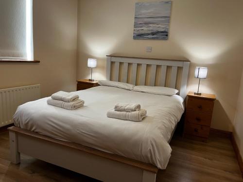 Un dormitorio con una cama blanca con toallas. en Ashdoon House, en Donegal