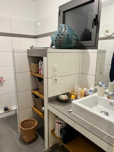 une salle de bain avec un lavabo et une télévision au mur dans l'établissement MAGNIFIQUE APPARTEMENT - Porto Vecchio, à Porto-Vecchio