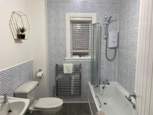 uma casa de banho com uma banheira, um WC e um lavatório. em Innisfree Self Catering Apartment, Banavie, Fort William em Fort William