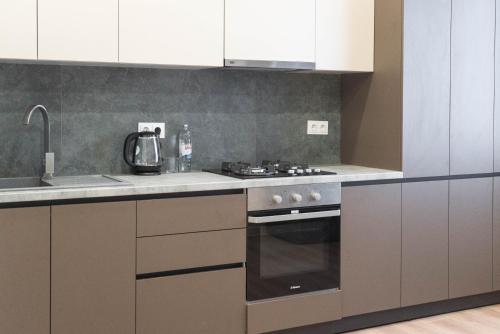 a kitchen with white cabinets and a stove top oven at RentWill apartments Oliva in Chişinău