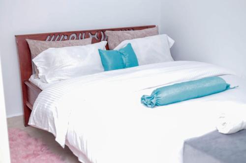 un letto bianco con cuscini blu e bianchi di Zoe Homes Greypoint 1br and 2bedroom Apartment 301 a Kericho