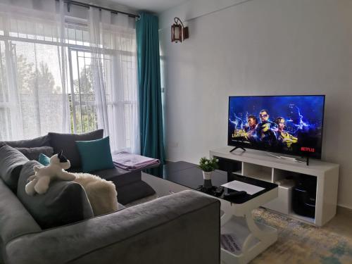 een woonkamer met een bank en een flatscreen-tv bij Zoe Homes Greypoint 1br and 2bedroom Apartment 301 in Kericho