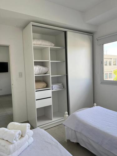 Apart hotel Magda في فينادو تيورتو: غرفة نوم مع خزانة بيضاء مع الوسائد وسرير