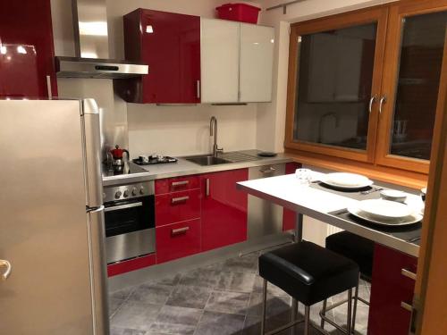 een keuken met rode kasten en een roestvrijstalen koelkast bij Appartamento nuovo e comfort a Brunico Kronplatz in Brunico