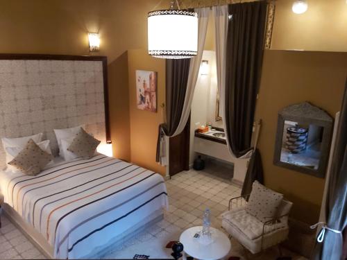 a hotel room with a bed and a chair at Riad Les Nuits de Marrakech in Marrakech