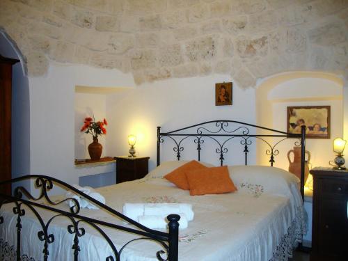 ein Schlafzimmer mit einem schwarzen Bett und einem orangefarbenen Kissen in der Unterkunft Trulli di Marì in Locorotondo