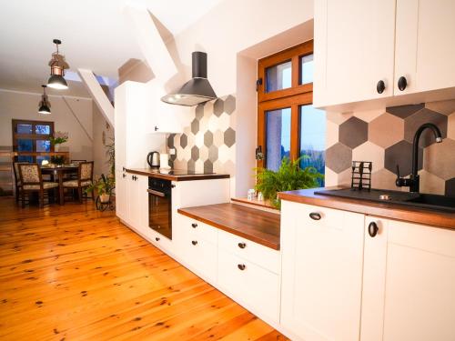 uma cozinha com armários brancos e piso em madeira em Młyn na Skraju Lasu 