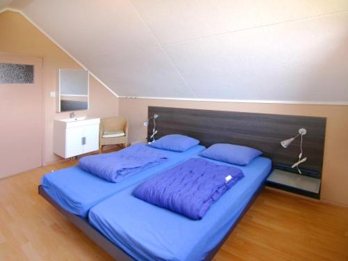 Schlafzimmer mit einem Bett mit blauer Bettwäsche und Kissen in der Unterkunft Jadi in Cadzand