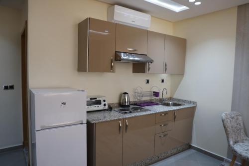 a kitchen with brown cabinets and a white refrigerator at RESIDENCE CENTROSUIT in Laayoune