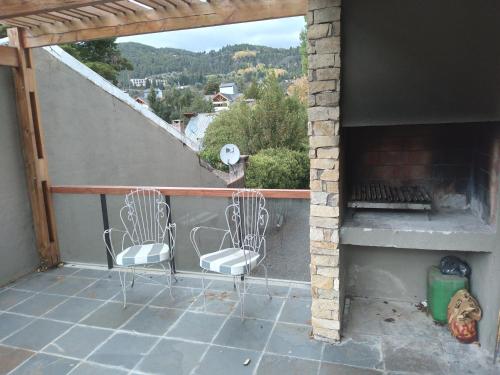 two chairs sitting on a balcony with a fireplace at Lo de Marcelo in San Martín de los Andes