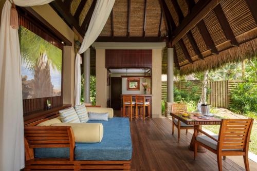 ein Wohnzimmer mit einem Sofa und einem Tisch in der Unterkunft Anantara Maia Seychelles Villas in Anse Boileau