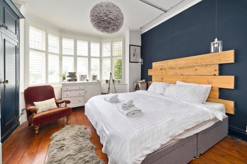 a bedroom with a large bed with a blue wall at Stunning one bedroom flat with large terrace in Chiswick by UnderTheDoormat in London