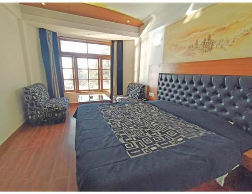 a bedroom with a large bed with two chairs and a window at Hotel Horizon Picture Palace, Mussoorie in Mussoorie