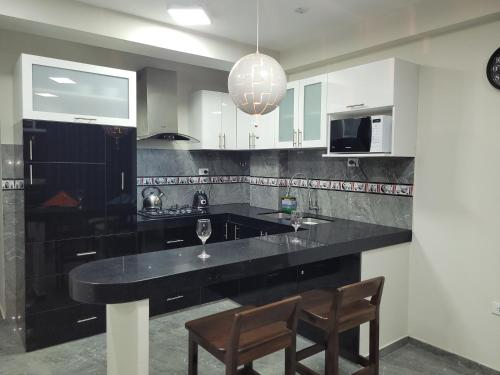 uma cozinha com um balcão preto e duas cadeiras em Apartamentos "APPART D'ELIETTE" em Trujillo