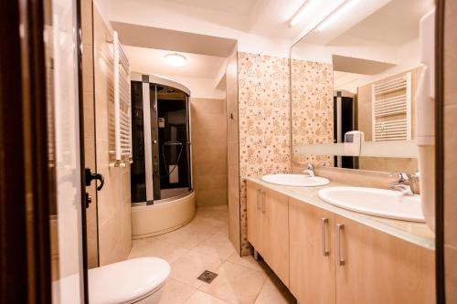 uma casa de banho com 2 lavatórios e um WC em Hotel Cindrel em Păltiniş
