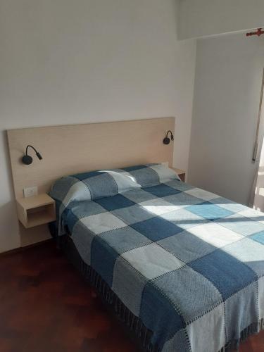 Un dormitorio con una cama con una manta de cuadros azul y blanco en alquiler temporario en Rosario