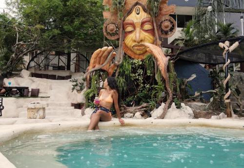 a woman sitting in a swimming pool next to a statue at ME Hotel & Villas - Montañita Estates in Montañita