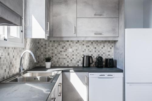 una cocina con armarios blancos y fregadero en Enjoyable 2BR Apartment in Marousi by UPSTREET en Athens