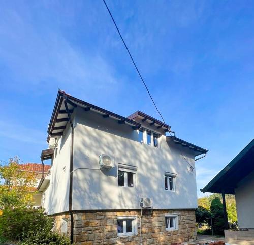 a white house with a roof at Apartmani Mir A1 in Vrnjačka Banja