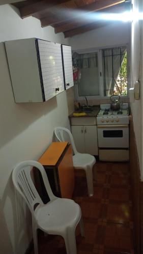 cocina con 2 sillas, mesa y fogones en Departamentos Urquiza 2 en Mendoza