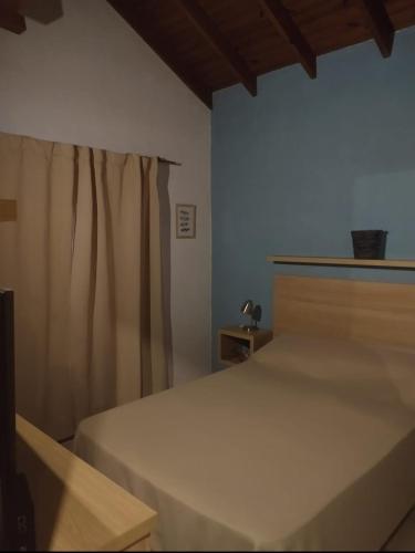 1 dormitorio con cama blanca y cortina en Maria en Villa Gesell