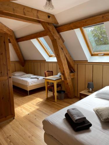 a attic bedroom with two beds and a table at l'Ancienne Ecole du Villard in Saint-Pierre-dʼEntremont
