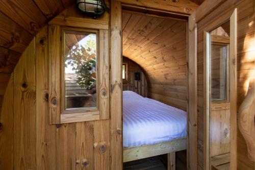 1 dormitorio en una cabaña de madera con 1 cama. en Boomhuis met optioneel wellness - Vakantiepark de Schreiershoek en Dokkum