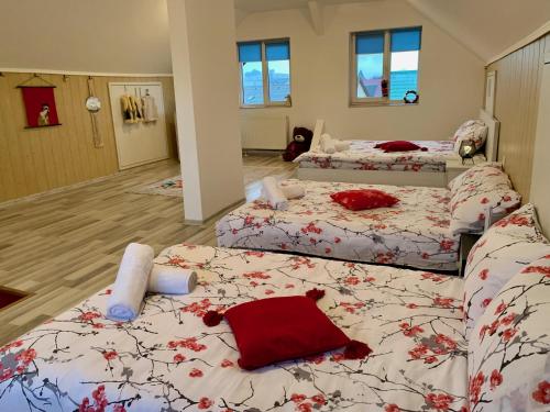 Un dormitorio con tres camas con almohadas rojas sobre ellas. en Casa Costache, en Brasov