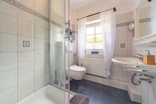 uma casa de banho com uma banheira, um lavatório e um WC. em Ferienwohnung Lüttje Huck - Seeblick 3 em Aurich