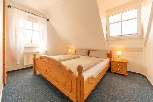 um quarto com uma cama de madeira e 2 janelas em Ferienwohnung Lüttje Huck - Seeblick 3 em Aurich