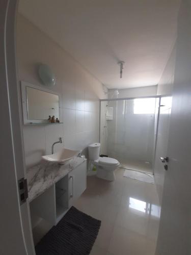 a white bathroom with a toilet and a sink at Belo apto a 100 metros da praia in Porto Belo