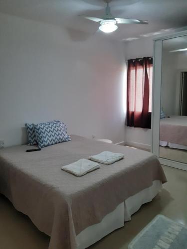 een slaapkamer met een groot bed en 2 handdoeken bij Belo apto a 100 metros da praia in Porto Belo