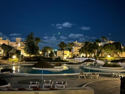 een zwembad 's nachts met stoelen en gebouwen bij Apartamento Jameos-Los Molinos Costa Teguise, Lanzarote in Costa Teguise