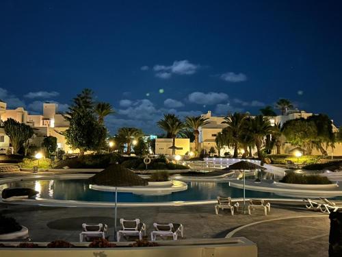 Una piscina de noche con sillas y edificios. en Apartamento Jameos-Los Molinos Costa Teguise, Lanzarote, en Costa Teguise