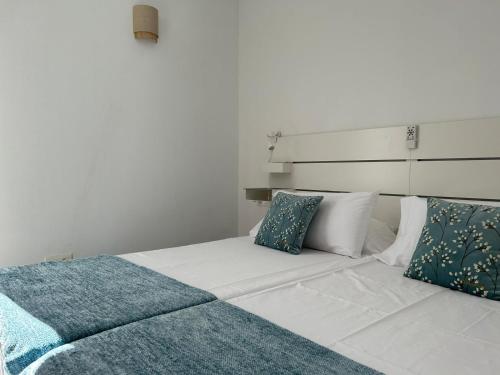Un dormitorio con una cama blanca con almohadas azules y blancas. en Apartamento Jameos-Los Molinos Costa Teguise, Lanzarote, en Costa Teguise